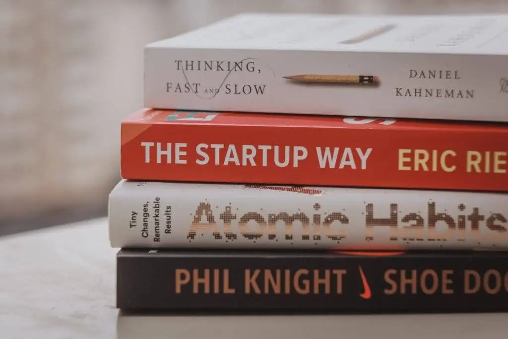 A stack of books about mindset and building habits like "Think, Fast and Slow" , "The Startup Way", "Shoe Dog" and "Atomic Habits"