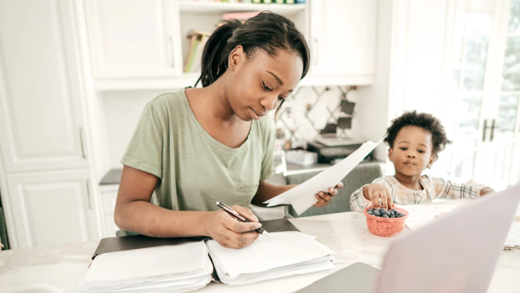A mother working out her tax financials with her son in the kitchen