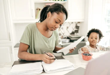 A mother working out her tax financials with her son in the kitchen