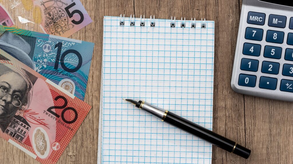 Notebook and calculator with Australian dollars, planning finances for superannuation tax.