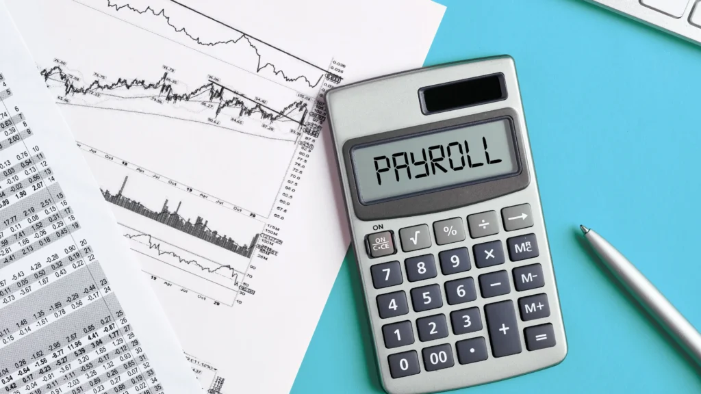 Payroll text on a calculator display surrounded by financial planning documents